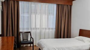 A hotel room with two beds, a wooden desk, a chair, and a window with sheer curtains. - Yandangshan Xiankelai Villa (Yueqing)