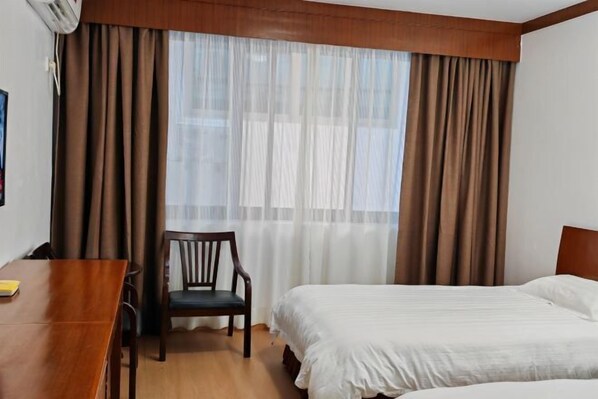 A hotel room with a bed, a chair, a table, and a window with curtains. - Yandangshan Xiankelai Villa (Yueqing)