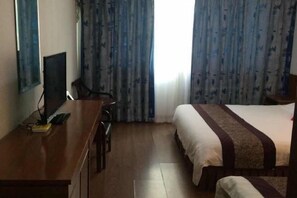 Una habitación de hotel con una cama, un escritorio con ordenador y cortinas.