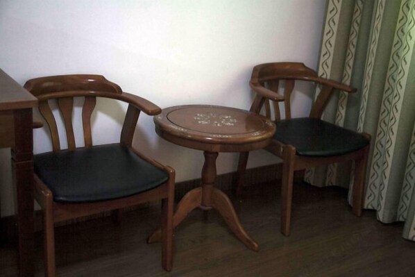 Un rincón con dos sillas de madera y una mesita redonda.