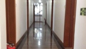 A long, narrow hallway with a shiny floor, wooden doors on either side, and a fire extinguisher on the left. - Yandangshan Xiankelai Villa (Yueqing)