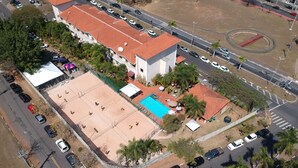 Vista aérea de un edificio con piscina, rodeado de coches aparcados y palmeras.
