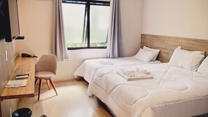 Habitación de hotel con cama, escritorio, silla y equipo de aire acondicionado.