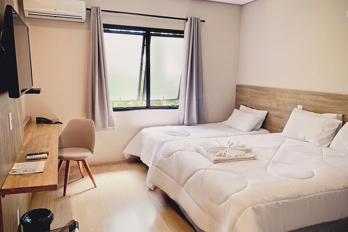 Ein Hotelzimmer mit einem Bett, einem Schreibtisch, einem Stuhl und einer Klimaanlage.