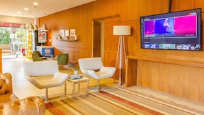 Un moderno vestíbulo con una televisión de pantalla plana, asientos cómodos y una pared de madera.