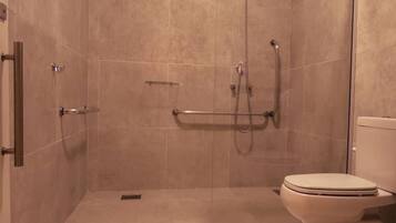 Un baño con ducha, inodoro y barra de apoyo.