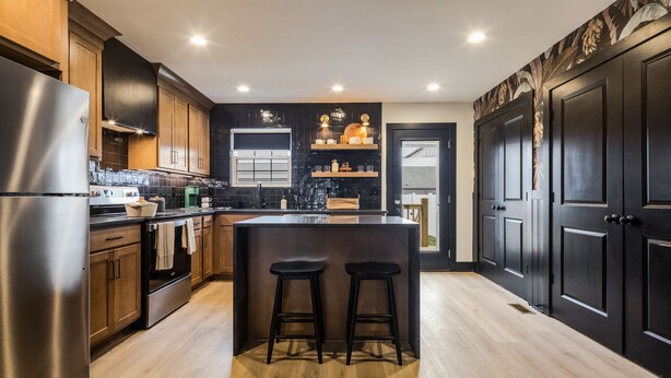 A modern kitchen with a central island, stainless steel appliances, and dark cabinetry. - The Winnie Lou (Jeffersonville)