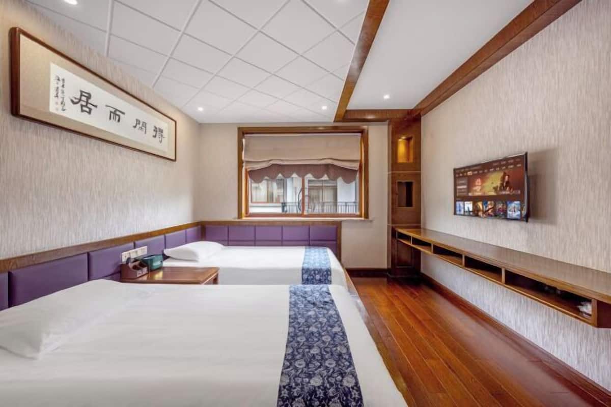 Une chambre d’hôtel avec deux lits, une télévision, une fenêtre donnant sur un paysage agréable et un panneau encadré accroché au mur.