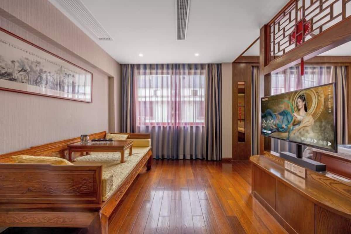Une chambre traditionnelle avec un plancher en bois, un canapé, une télévision et un tableau au mur.
