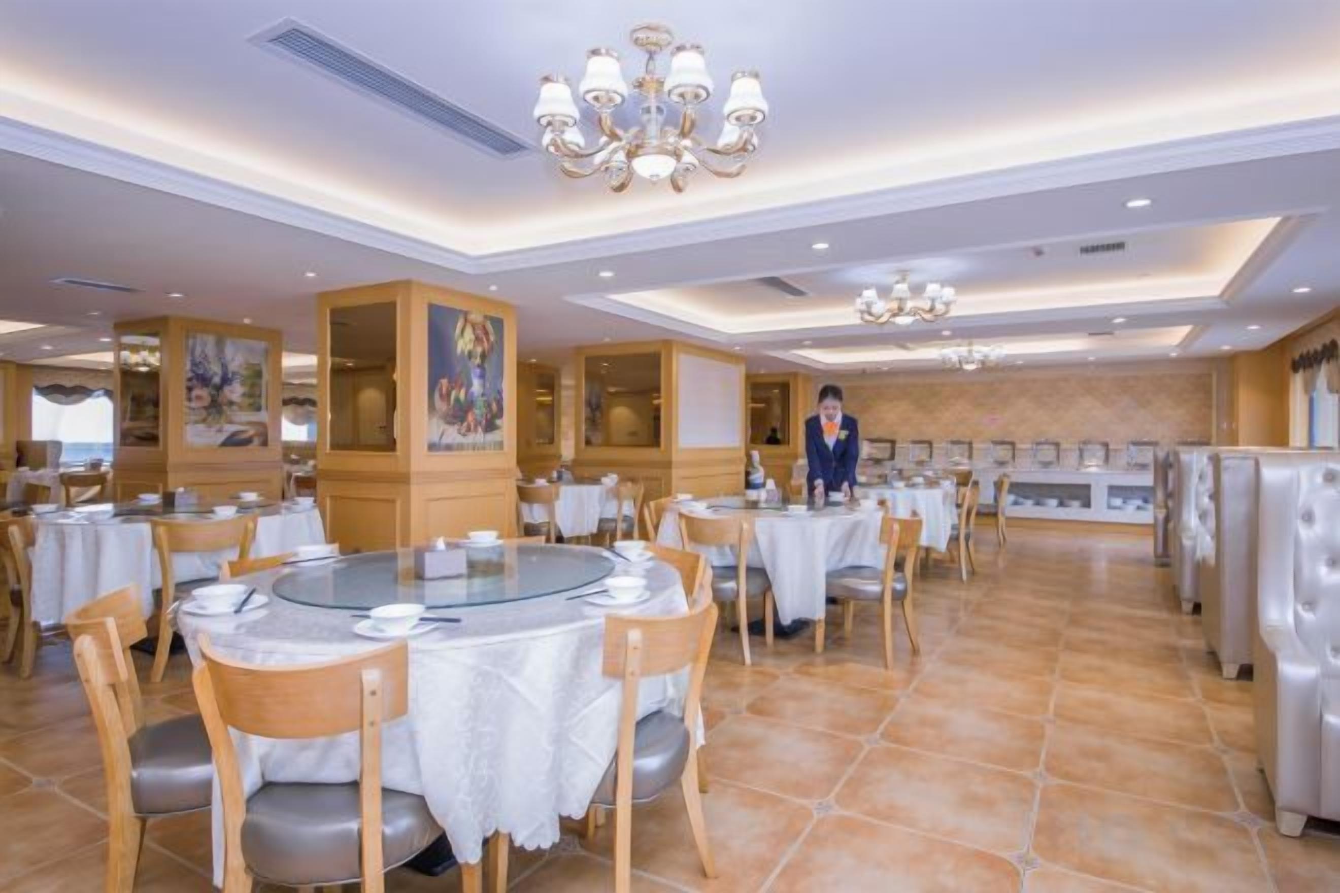 A restaurant with round tables, chairs, and a waiter.