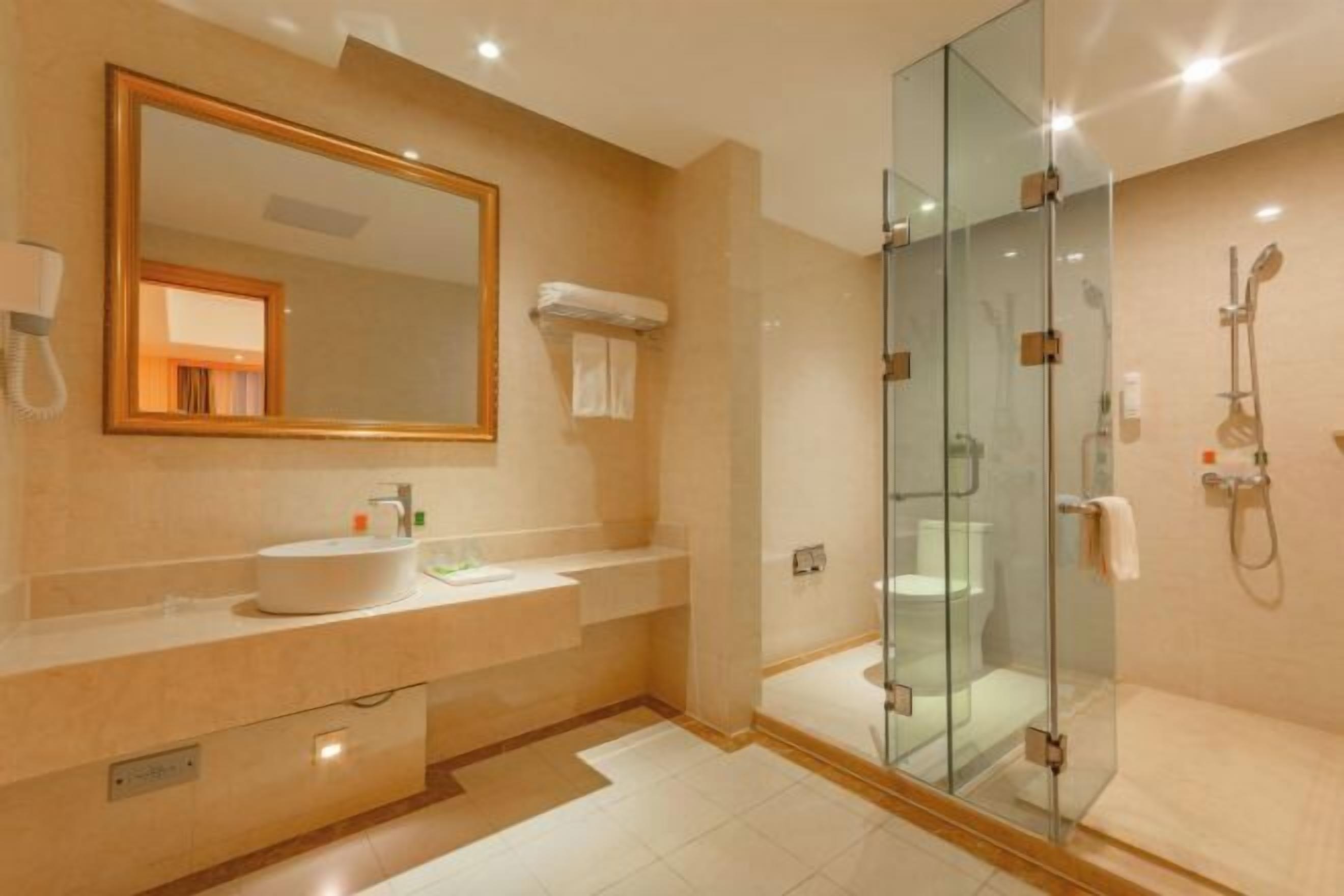 Un baño moderno con ducha de vidrio, un espejo grande y un lavabo blanco.