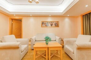 A room with a sofa set, a wooden table, a painting on the wall, and a door. - Vienna International Hotel (Hubei Province,Huanggang Dongmen Road) (Huanggang)