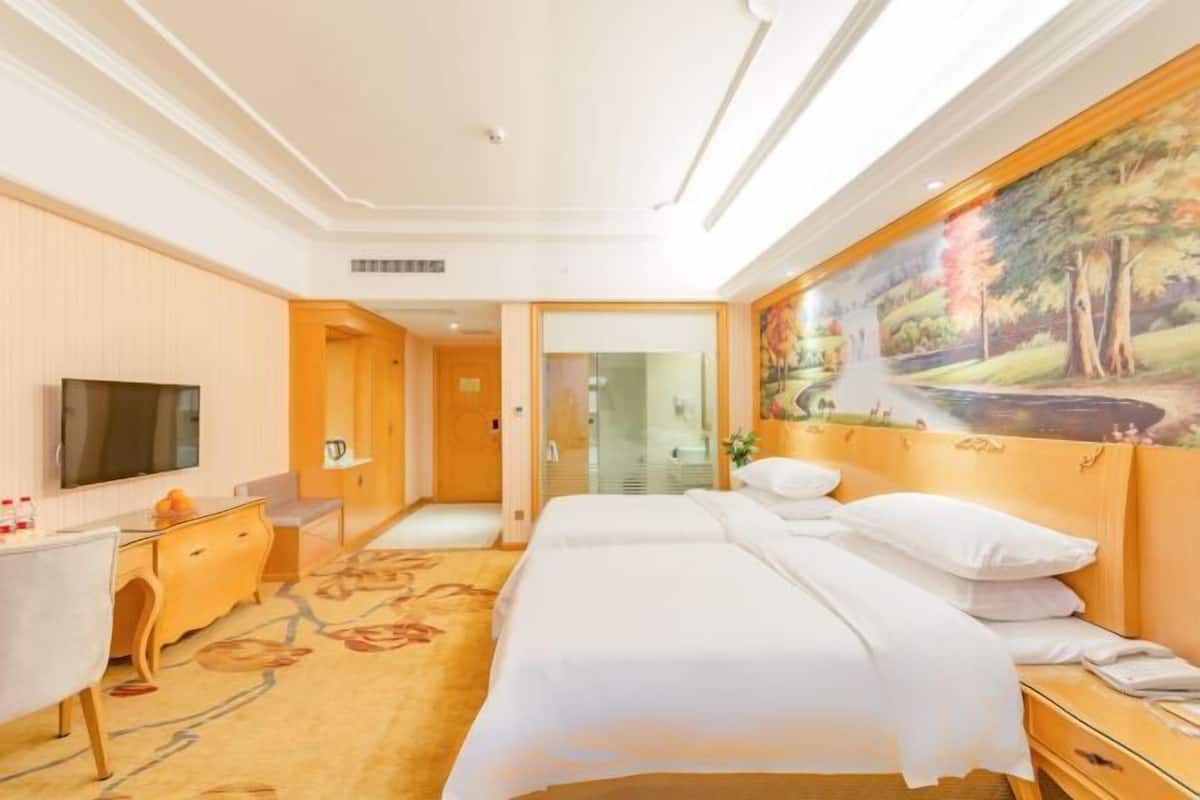 Habitación de hotel con cama, escritorio, televisor y un cuadro en la pared.