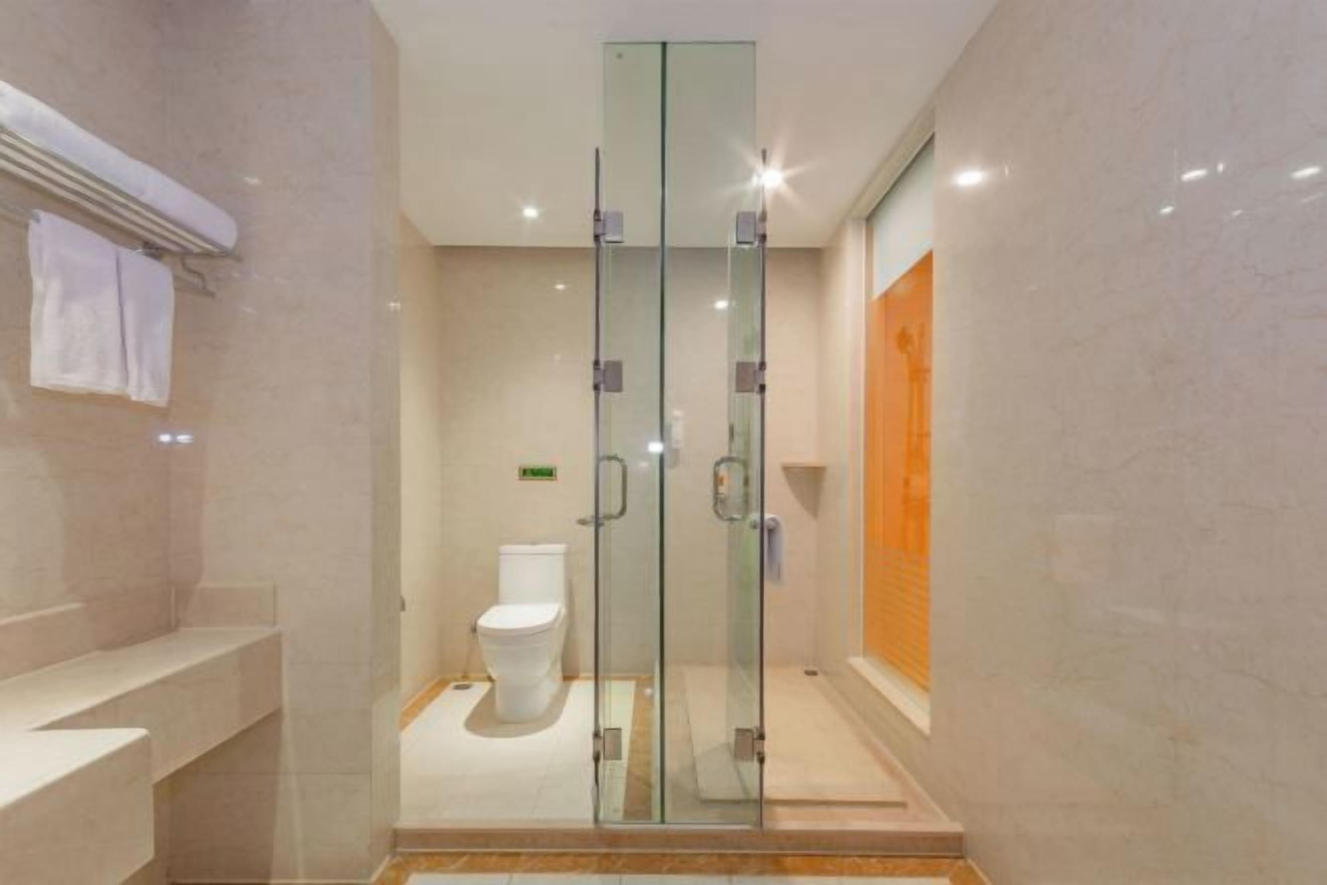 Een moderne badkamer met een douche met glazen wand, een toilet en een wastafel met een handdoekhouder.