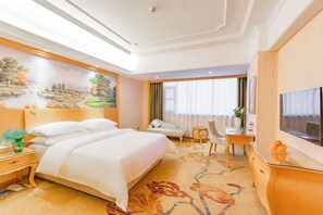 A hotel room with a large bed, a desk with a chair, a television, and a painting on the wall. - Vienna International Hotel (Hubei Province,Huanggang Dongmen Road) (Huanggang)
