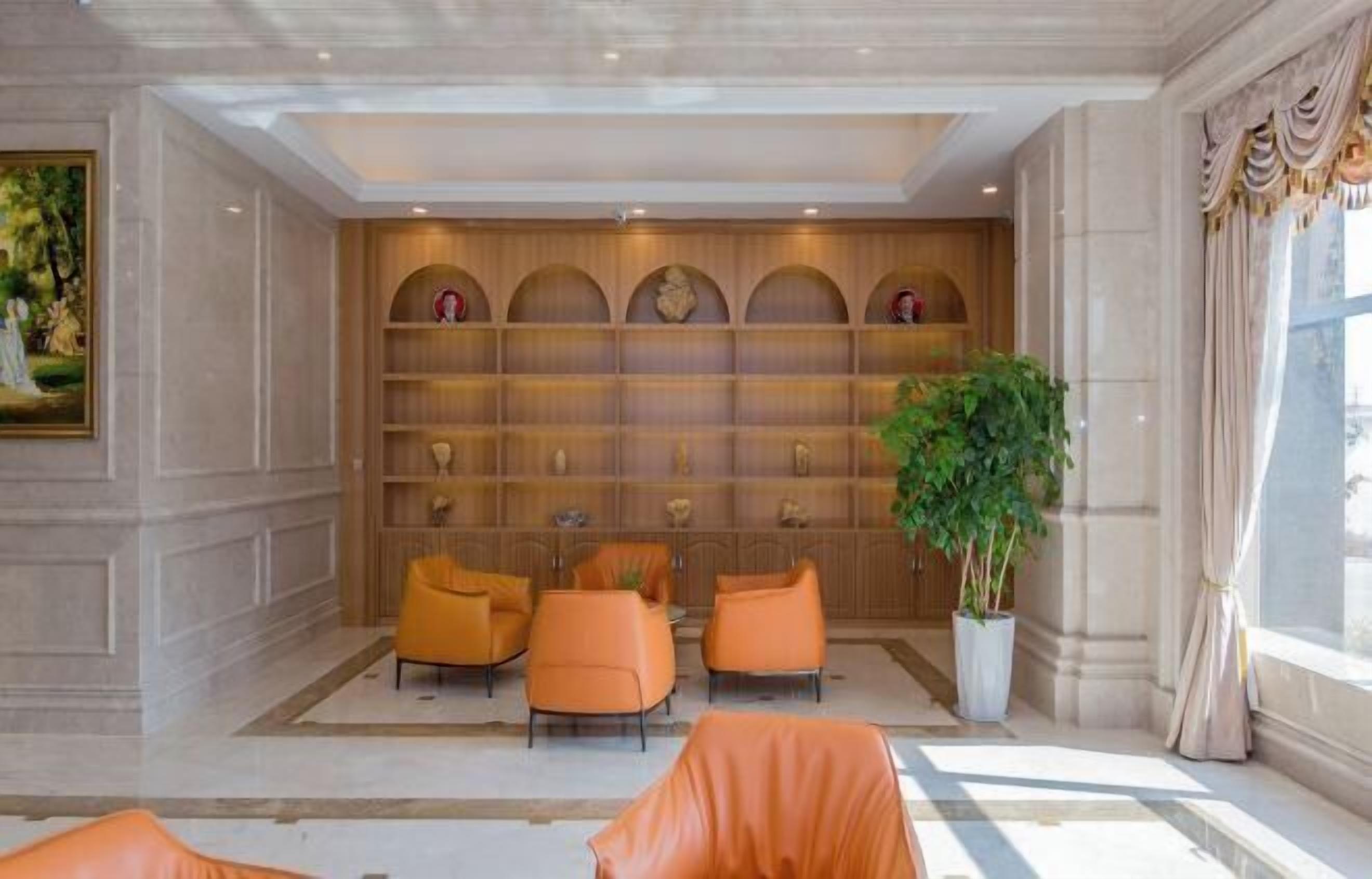 A lobby with a marble floor, a reception desk, and a seating area with orange chairs.