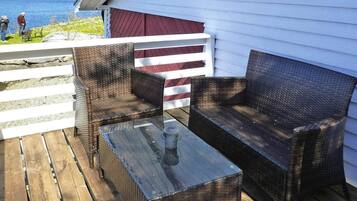 A wooden deck with wicker furniture and a glass table.