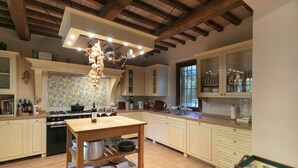 Una cocina amplia con vigas de madera, una isla central con espacio de almacenamiento y un ventanal que proporciona luz natural.