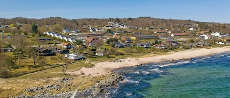 A coastal residential area with houses, a beach, and a rocky shoreline.