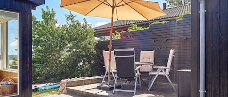 An outdoor patio with a table and chairs, a large umbrella, and a wooden fence.