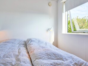 A bedroom with a bed, a window, and a wall-mounted light fixture.