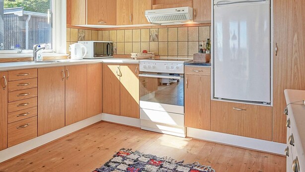Une cuisine de taille réduite, avec des meubles de rangement en bois, un réfrigérateur blanc, un four à micro-ondes et une cuisinière.