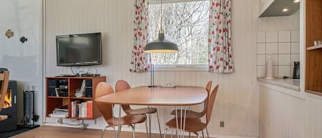 Una sala de estar acogedora con una mesa y sillas de madera, un televisor y una chimenea.