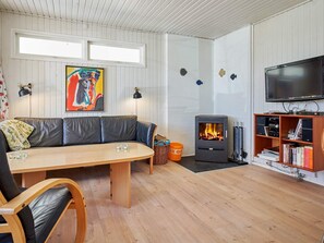 Een gezellige woonkamer met een bank, een houten tafel, een open haard, een televisie en een boekenkast.