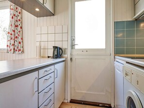 A kitchen with white cabinets, a kettle, and a washing machine. - 4 Person Holiday Home in Aakirkeby (Akirkeby)