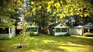 A row of single-story cabins with attached porches, surrounded by a well-maintained lawn and trees.