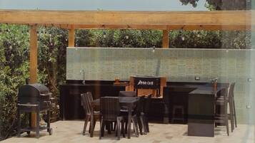 Terrassa exterior amb zona de graella, seients i una façana revestida de rajoles.