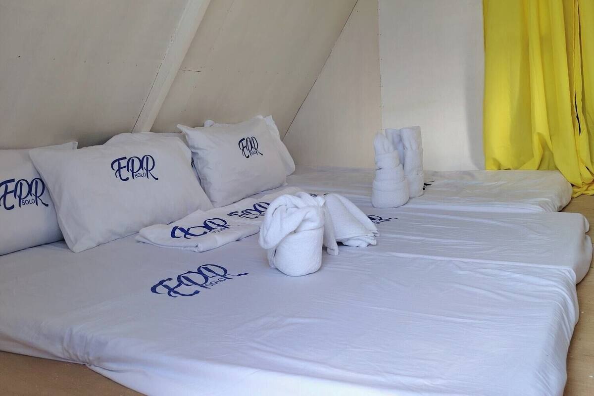 A hotel room with a bed, pillows, and towels.