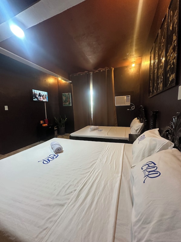 A hotel room with two beds, a flat-screen TV, a window with curtains, and artwork on the walls. - Emmalyn's Paradise Resort (San Andres)