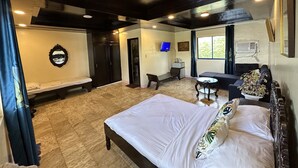 A hotel room with a large bed, a desk, a chair, a TV, and a window with curtains. - Emmalyn's Paradise Resort (San Andres)