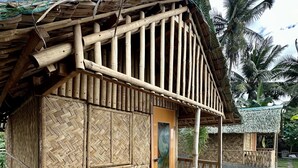 A bamboo hut with a thatched roof, a wooden door, and a small porch. - Emmalyn's Paradise Resort (San Andres)