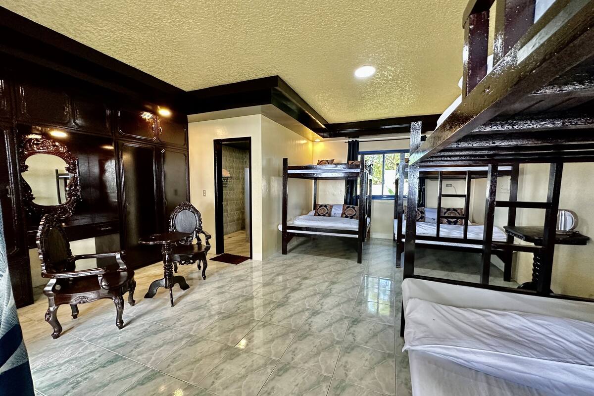 A room with bunk beds, a wooden chair, a mirror, and a tiled floor.