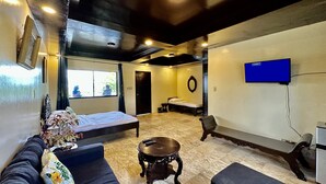 A room with a bed, a sofa, a small table, a TV, and a window with a view of the outside. - Emmalyn's Paradise Resort (San Andres)