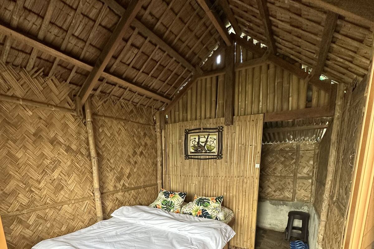 A room with a wooden bed, a woven ceiling, and a patterned floor.