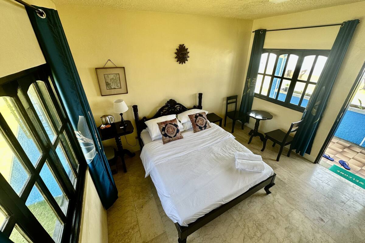 A hotel room with a bed, a desk, a chair, and a window with curtains.