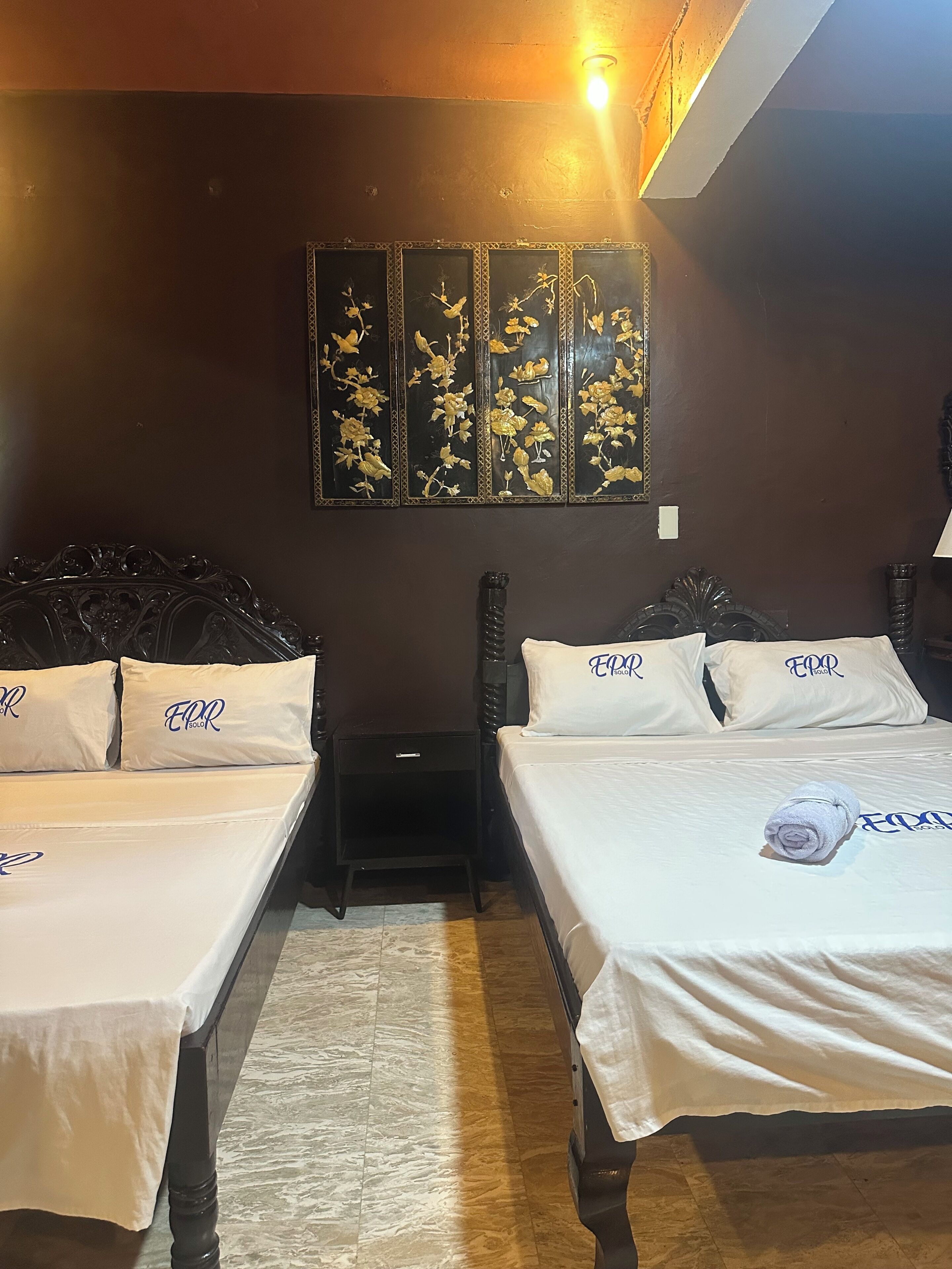 A hotel room with two beds, a nightstand, and a wall-mounted decorative panel.