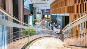 A modern interior with a glass staircase, wooden paneling, and a reception area. - Guiyang Wufang Zhixuan Hotel (Guiyang)