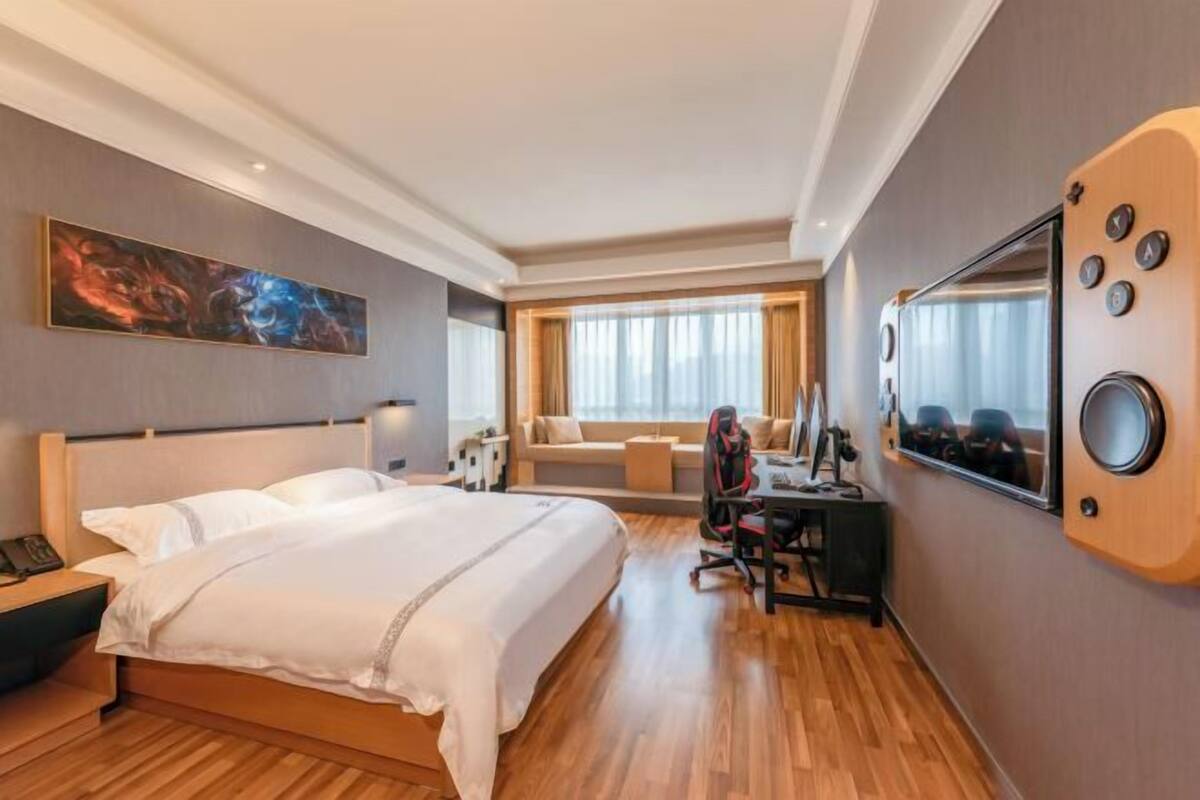 Une chambre d’hôtel avec un lit, un bureau, une chaise et une grande fenêtre avec des rideaux.