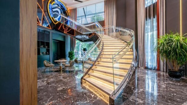 A modern interior with a glass staircase, marble flooring, and a vibrant geometric light installation. - Guiyang Wufang Zhixuan Hotel (Guiyang)