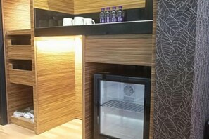 Una cocina compacta con refrigerador empotrado, armarios de madera y un revestimiento de pared estampado.