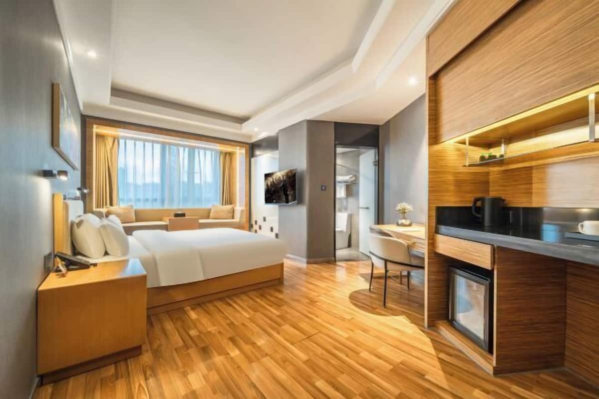 Une chambre d’hôtel moderne équipée d’un lit, d’une table de chevet, d’un bureau, d’une chaise, d’une télévision et d’une kitchenette.