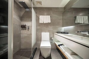 Een moderne badkamer met een douche, toilet en wastafel met spiegel.