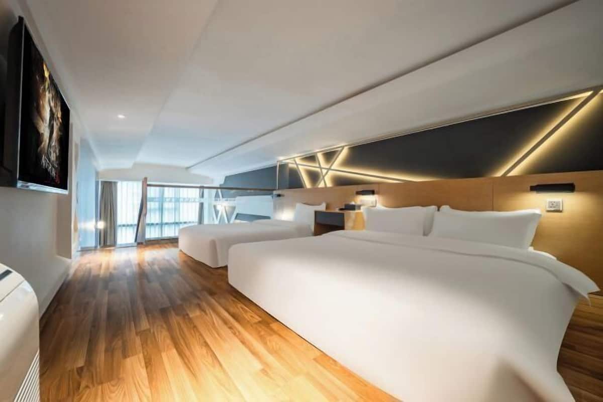 Une chambre d’hôtel moderne avec un grand lit, un lit plus petit et un coin salon.