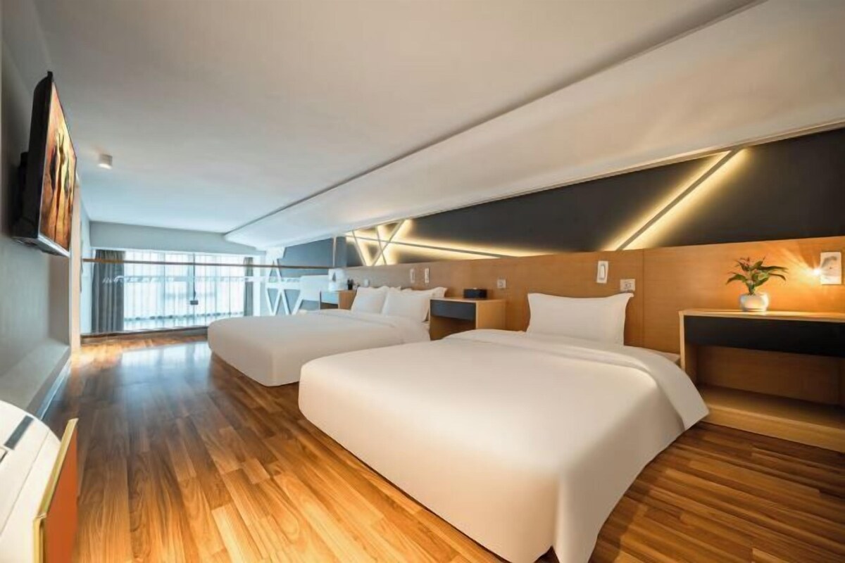 Een moderne hotelkamer met twee bedden, houten vloeren, een groot raam en uitzicht op de stad.