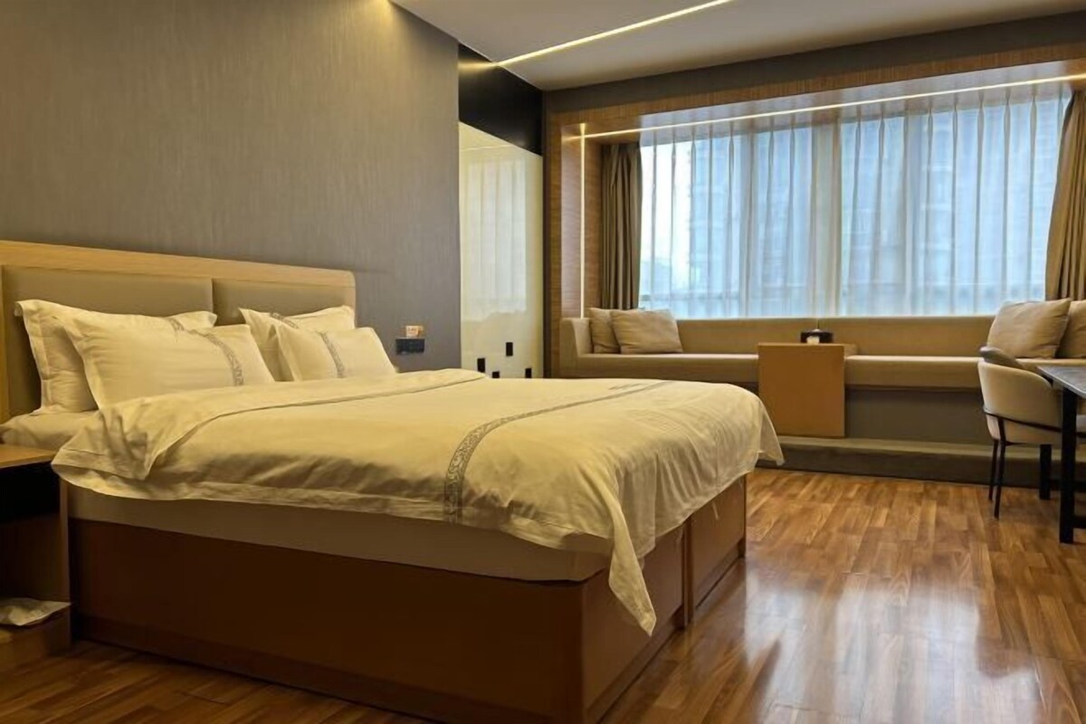 Een moderne hotelkamer met een groot bed, een bureau en een raam met gordijnen.