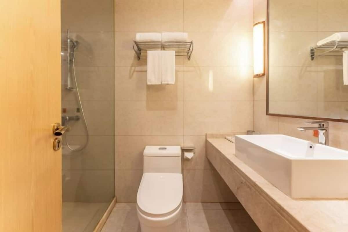 Un baño moderno con inodoro, ducha, lavamanos y espejo.